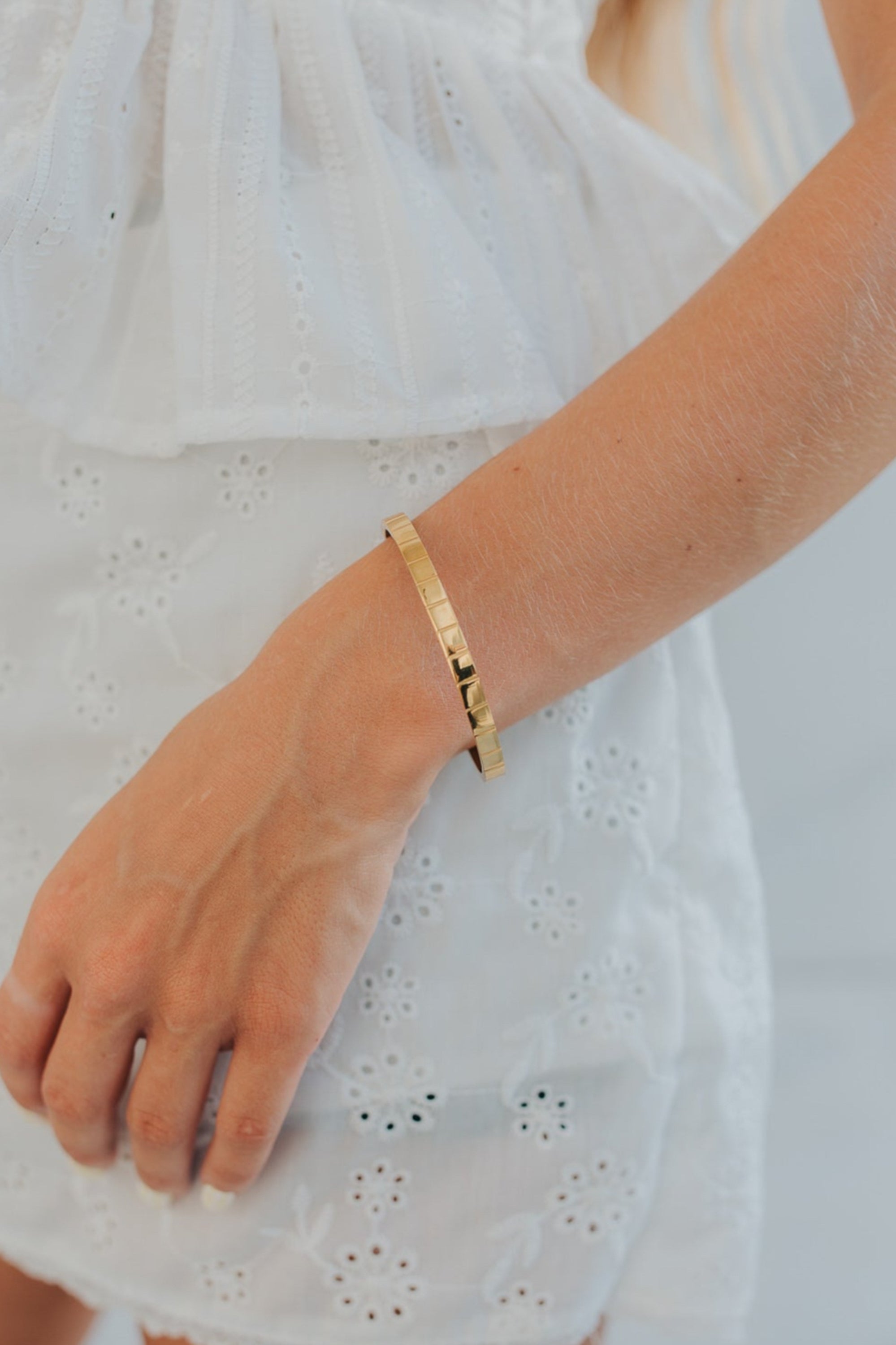 Close composition of the Lily Bracelet reflecting light on its high-gloss gold-plated finish and showcasing bevel edge craftsmanship.