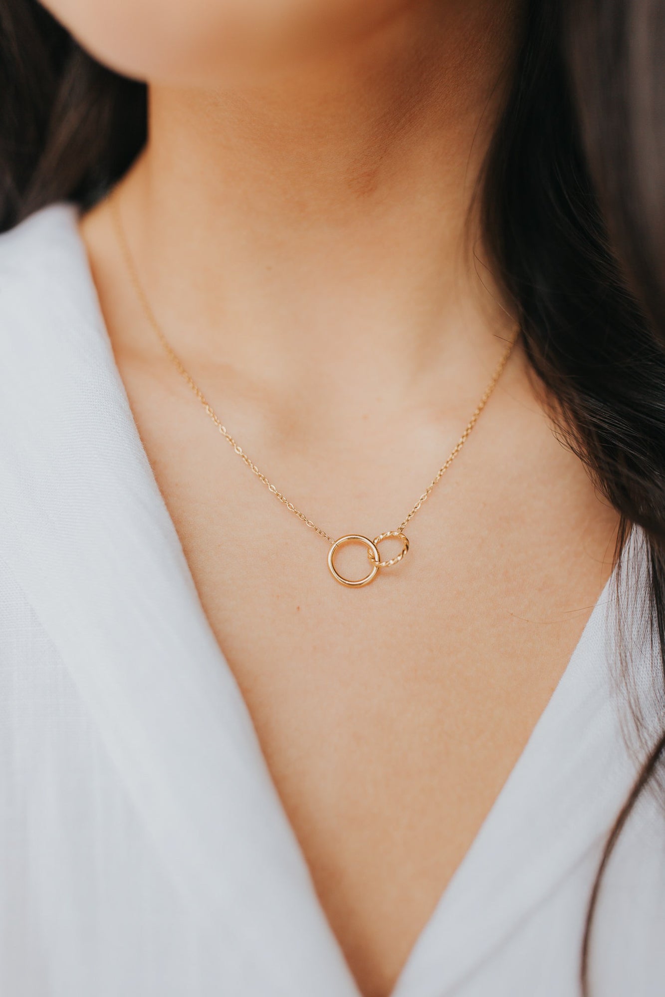 Artist-view image of The Mia Necklace highlighting the contrast between the smooth and textured gold circles and adjustable clasp.