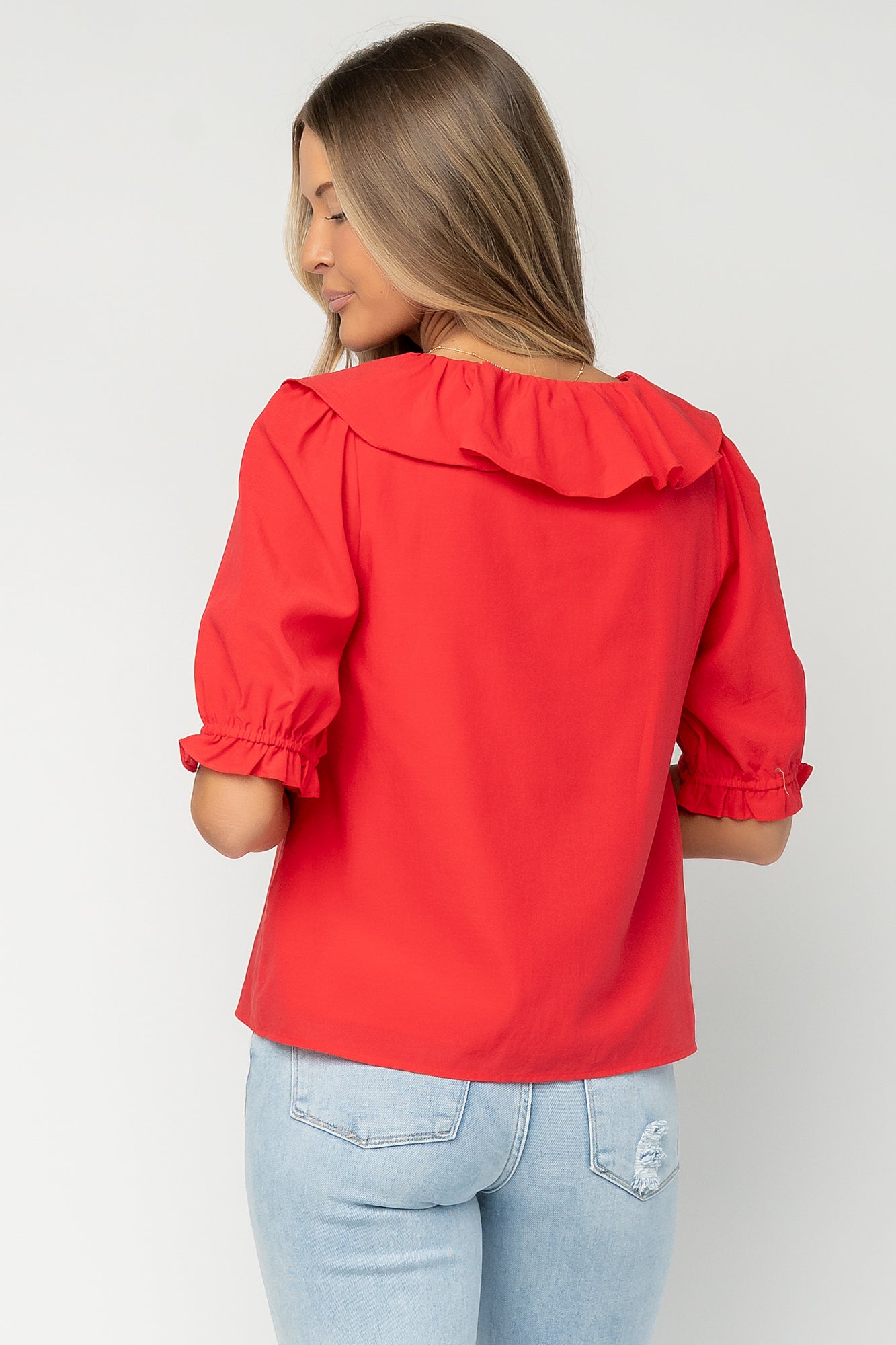 Close-up of the Daisy top’s button-front placket, delicate ruffle trim, and lightweight cotton-modal fabric texture in red.