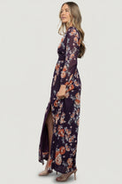 Styled full-length shot of the Adira Plum Floral Maxi Dress on a model, showing overall silhouette, length, and occasion-ready styling.