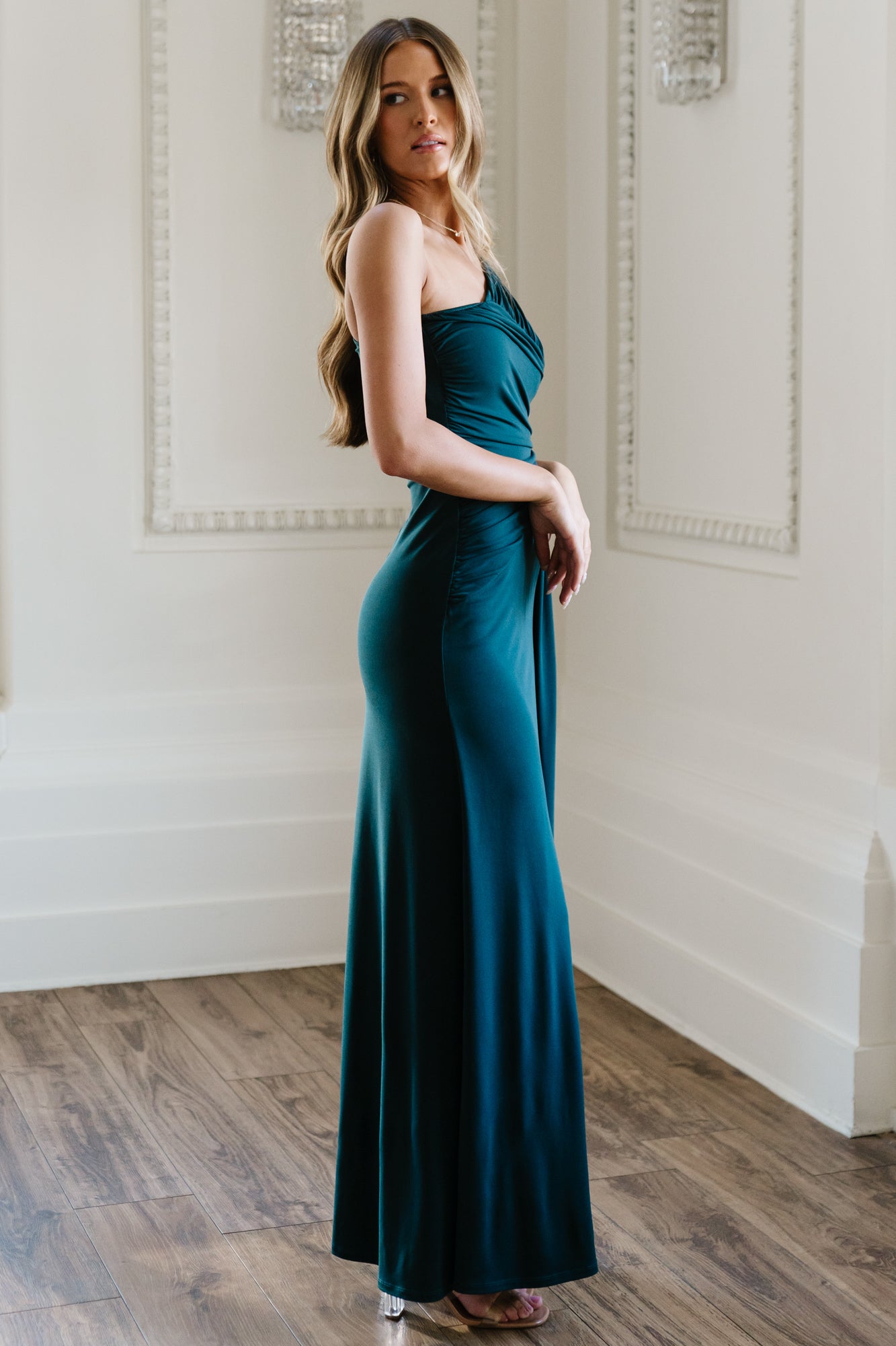 Model walking in Adrianna deep topaz gown, showing skirt movement and graceful floor-length sweep in evening lighting.