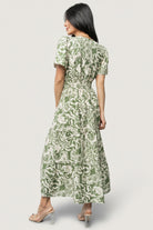 Back view of dress showing gathered sleeve detail, relaxed fit through the bodice, and tiered skirt silhouette in green floral print.