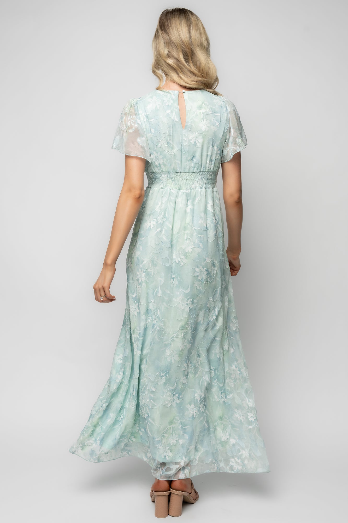 Close-up of the dress bodice showing smocked waist detail, V-neck finish, short flutter sleeve edge, and burnout velvet floral pattern.