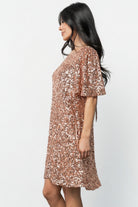 Side view of the rose gold Asta dress on model, focusing on the hidden side pocket and smooth shift silhouette.
