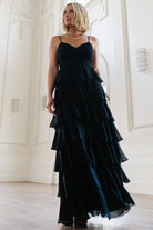Front view of Tiana Tiered Chiffon Maxi Dress in black on model, showing V-neck, gathered bust, adjustable spaghetti straps, and layered ruffle skirt.