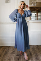 Model wearing dusty blue Dione georgette midi dress, front view showing sweetheart neckline, knotted bust, empire waist and puffed sleeves.