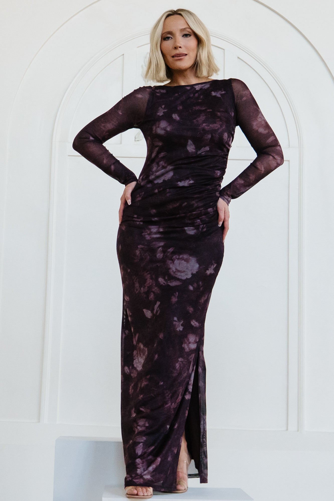 Front view of Isadora Maxi Dress in deep plum floral mesh, showing long sheer sleeves, round neckline and bodycon silhouette with left slit.