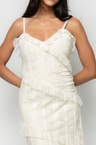 Detail close-up of cream lace fabric and diagonal tiered panel seams showing lace pattern, stitch detail, and buttery soft lining edge.