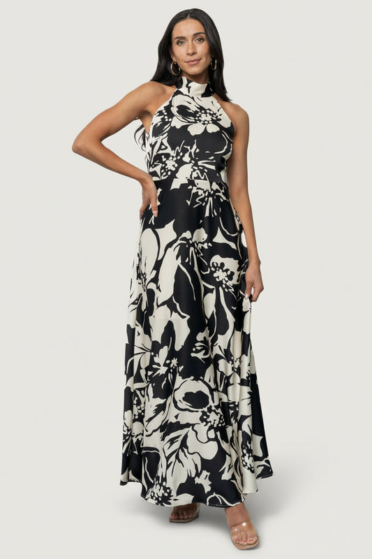 Three-quarter view of the Melodía Halter Maxi in black and ivory floral, highlighting the drape and skirt movement on model.