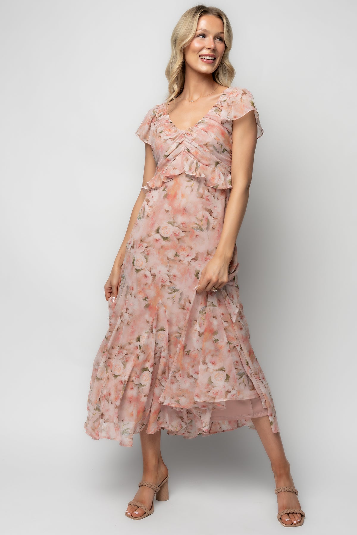 Full-length front view of Teuila Midi Dress in blush floral chiffon, showing V-neck, ruched bust, smocked back, and godet ruffle skirt.