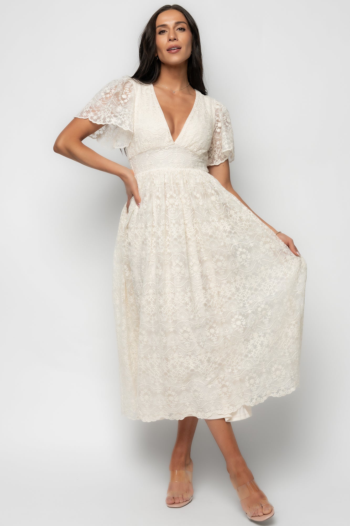 Model wearing the Aphrodite Lace Midi Dress in vintage cream, front view showing V-neckline and gathered waist for a feminine silhouette.