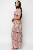 Styled outfit shot of the Montaigne Ruffle Maxi Dress in mauve floral with flowing tiers and asymmetrical ruffle detail.