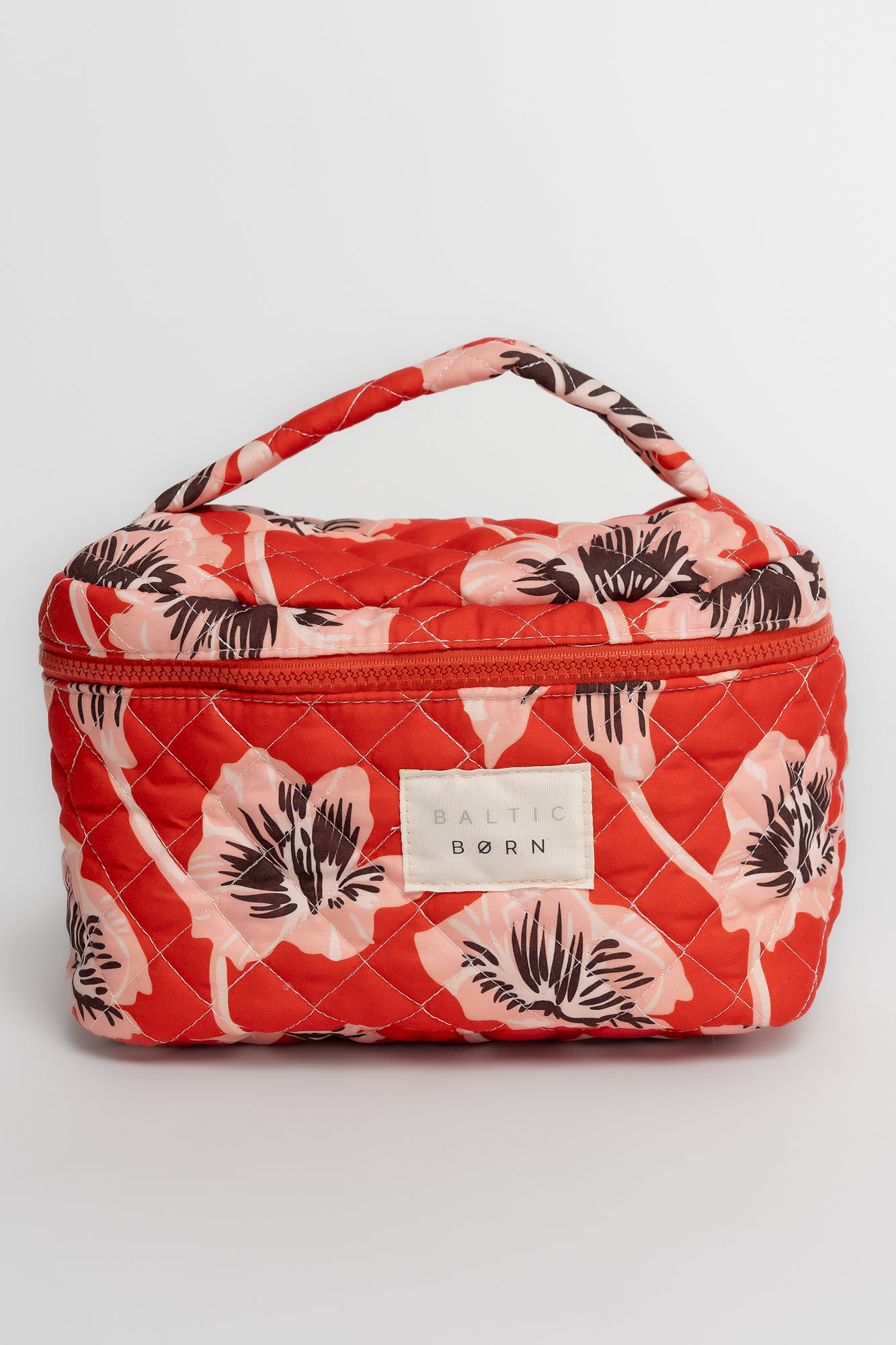 Three quilted cosmetic bags in sunset floral print displayed side-by-side on a light gray background to show scale and pattern.