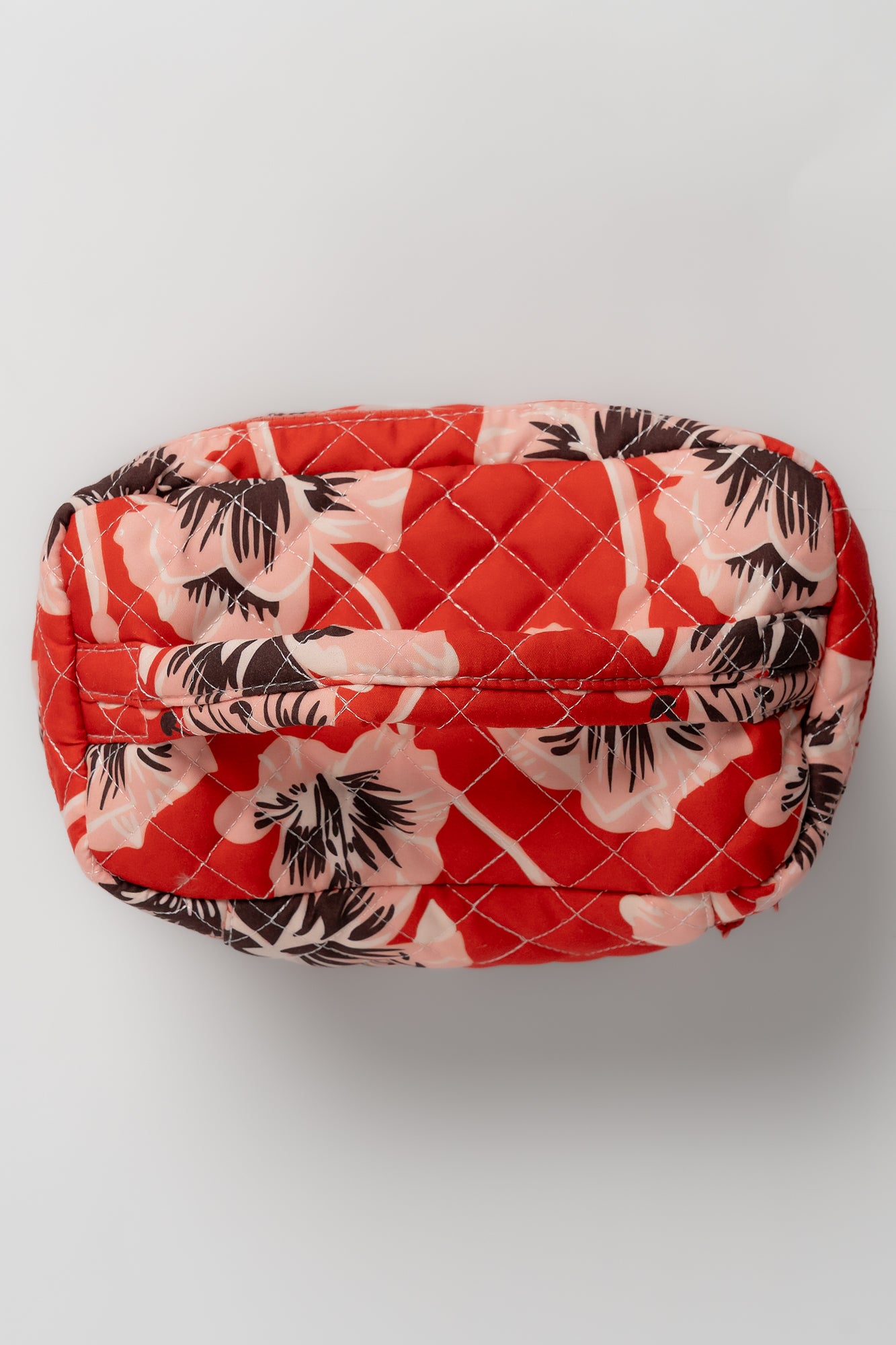 Front view of three coordinating quilted bags nested together in sunset floral, highlighting quilted texture and zipper placement.