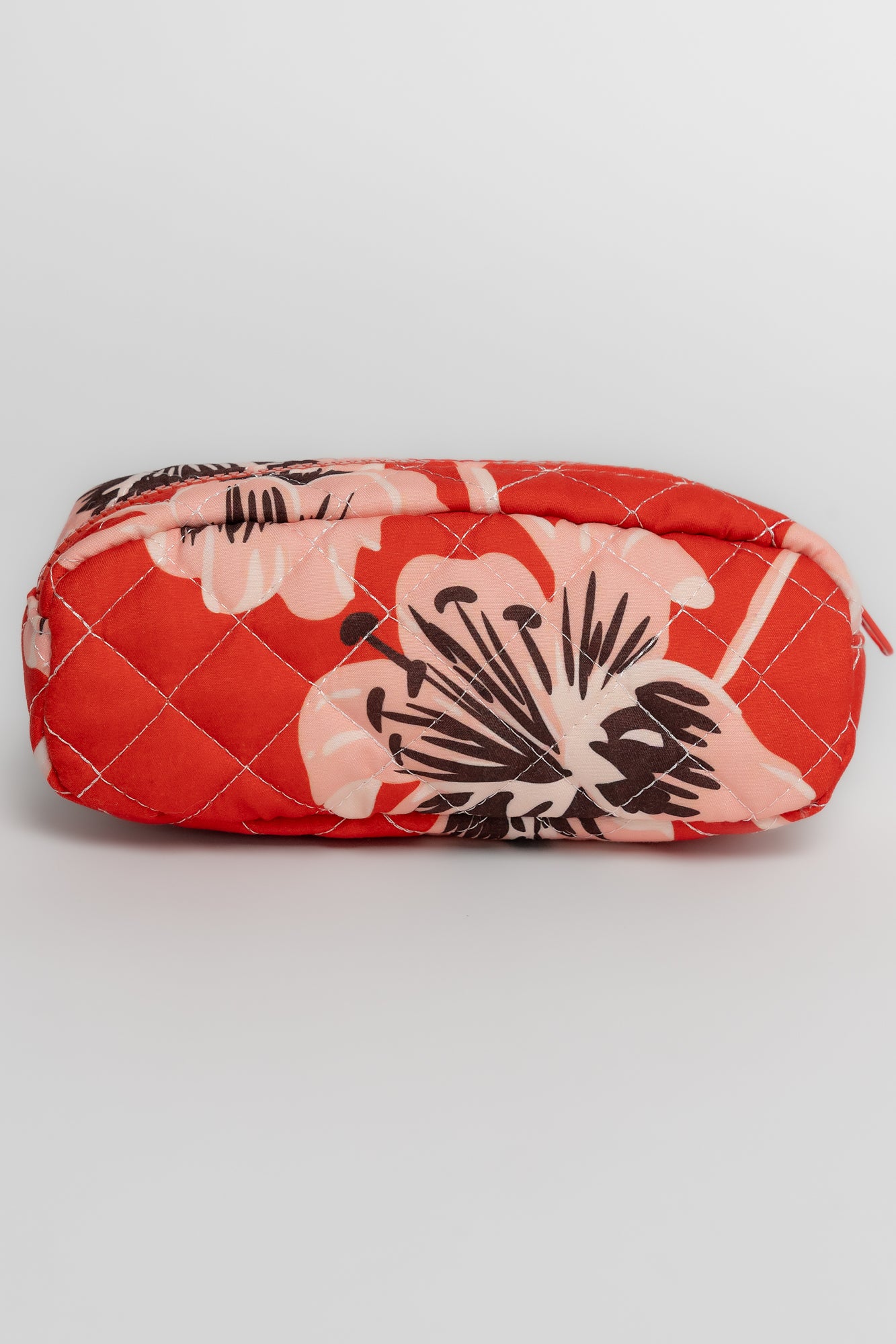 The largest quilted cosmetic bag with its small top handle visible, accompanied by medium and small coordinating bags beside it.