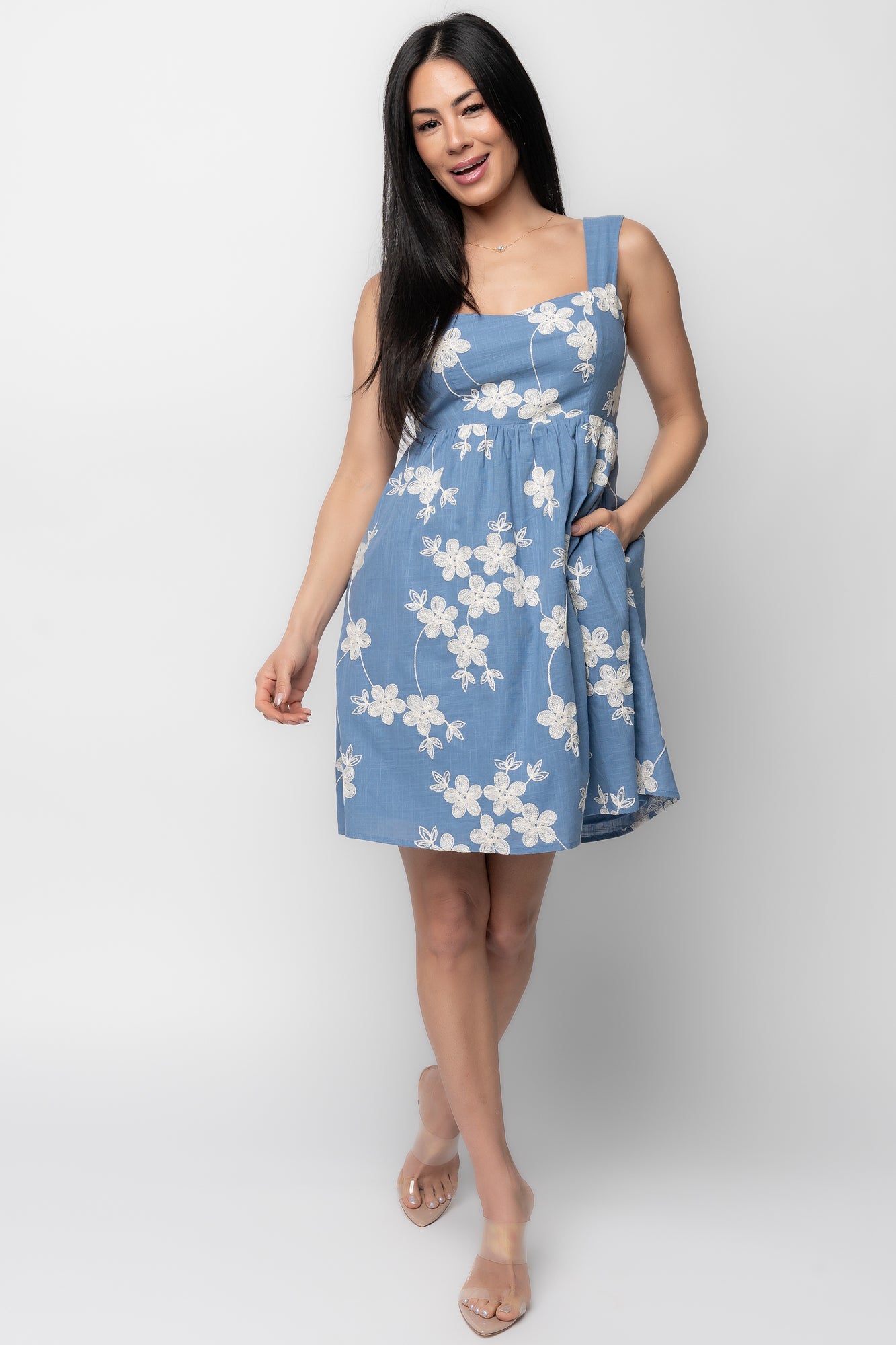 Front view of model wearing Ivy Short Dress in muted blue with off-white embroidered florals, square neckline and tank straps, full outfit.