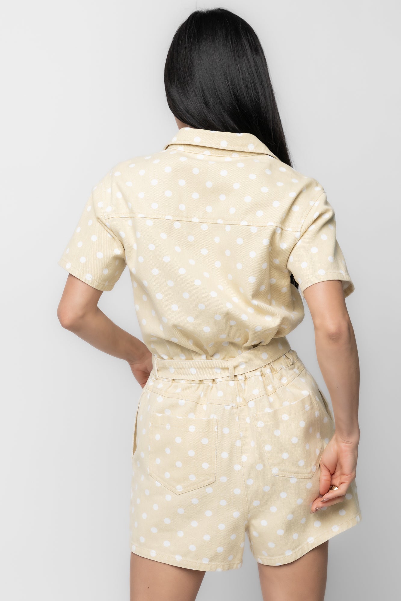 Close-up of fabric and print: light yellow twill denim woven texture with white polka dots and reinforced stitching.