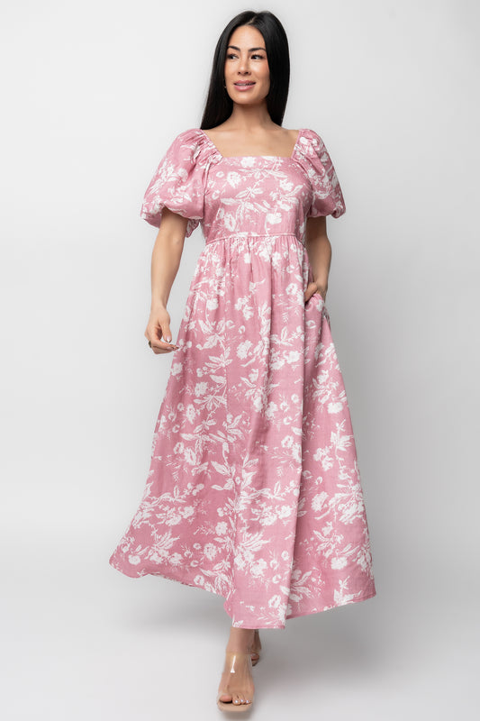 Model front view of pink maxi dress with white floral print, square neckline, puffed balloon sleeves, high waist and flowing A-line skirt.