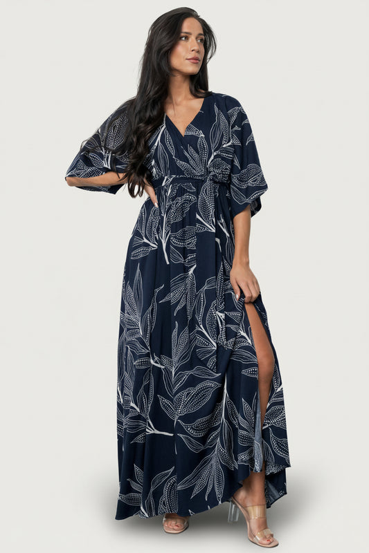 Side view of Kalea maxi dress showing left-side leg slit, elastic waistband and flowing rayon skirt with botanical print, model in motion.