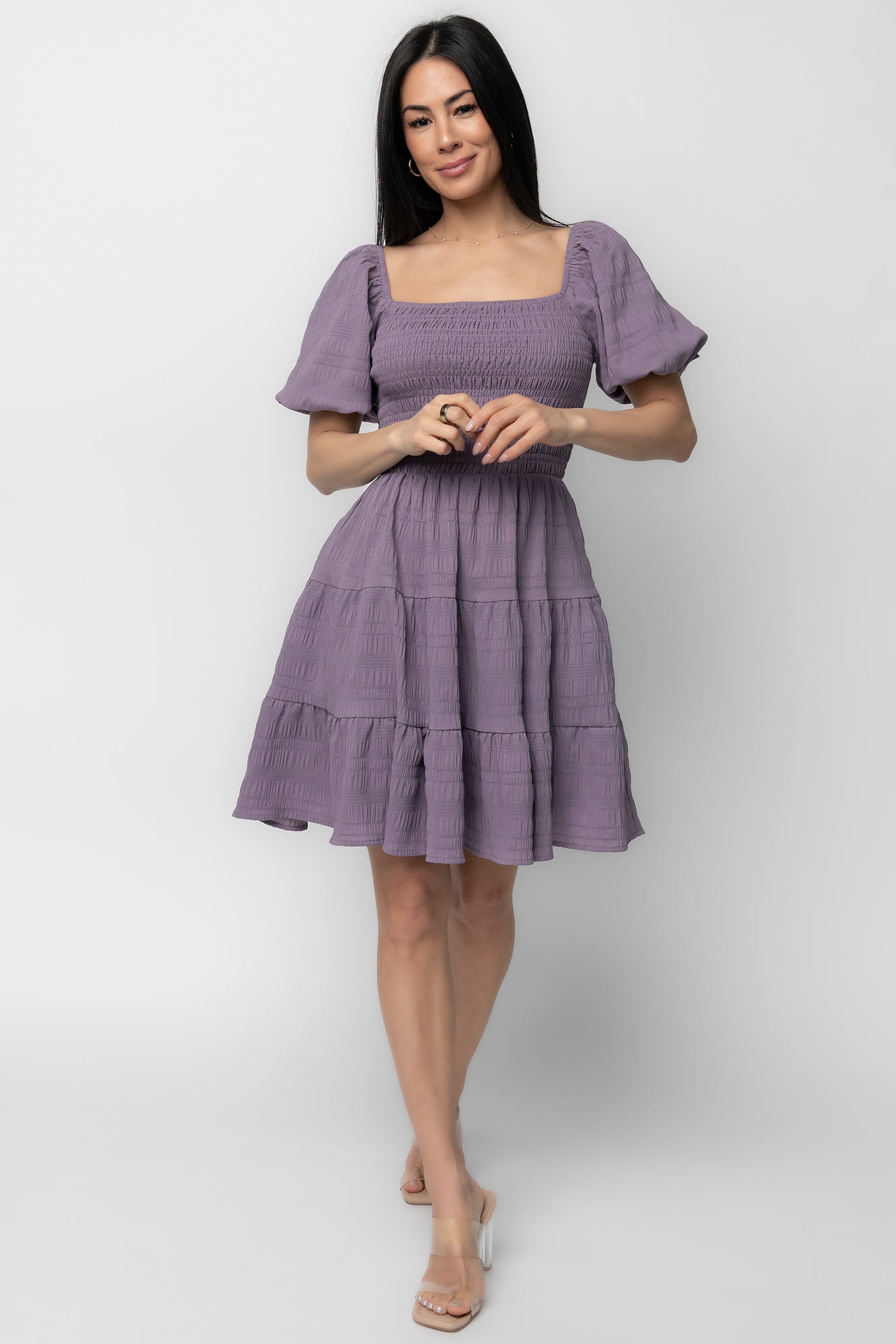 Front view of model wearing Daze Smocked Dress in dusty lavender showing square neckline, smocked bodice and three-tier short skirt.