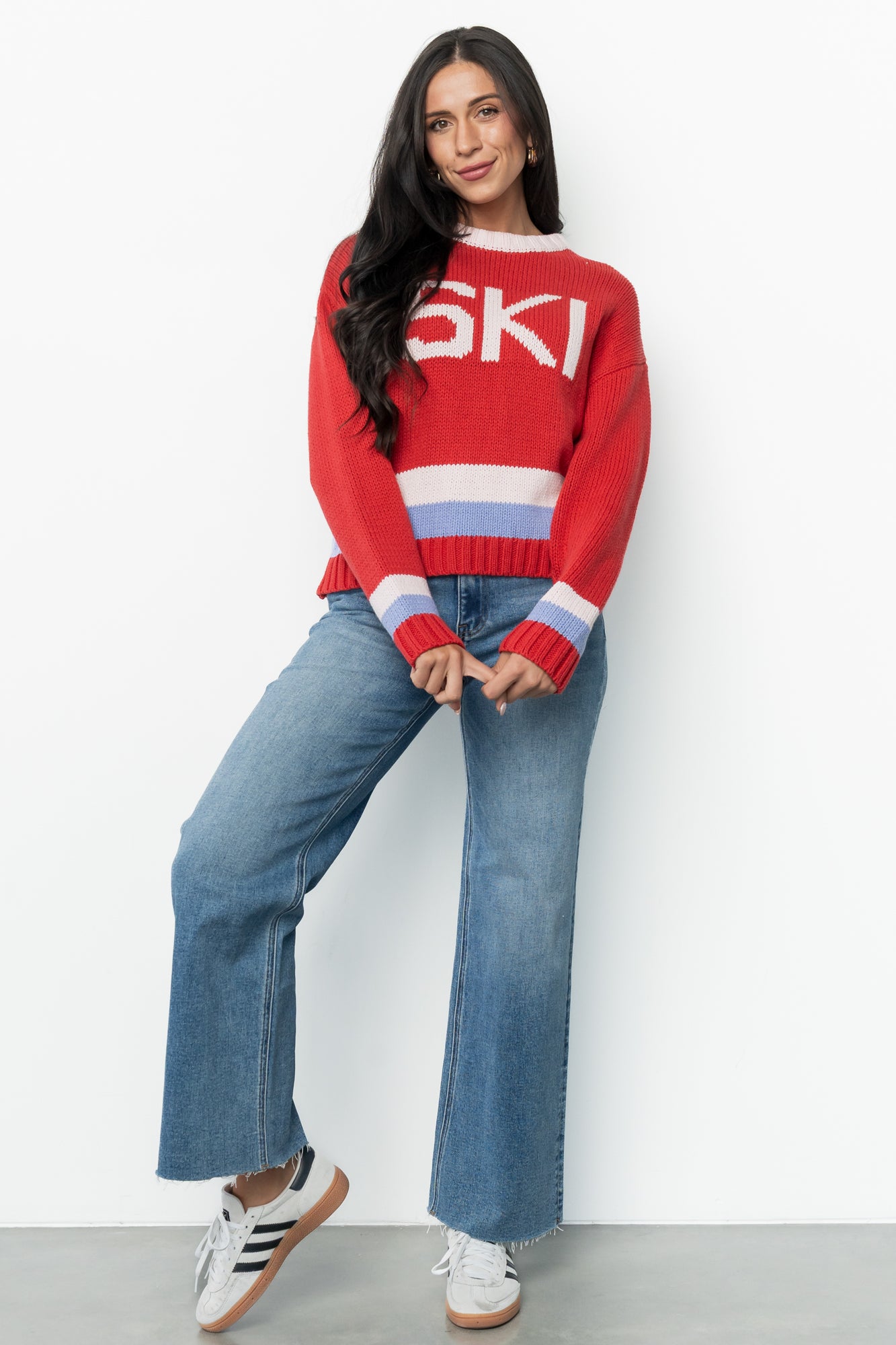 Model wearing the red multi Gilli ski sweater styled with jeans; shows relaxed silhouette, drop shoulder sleeves, and playful color accents.