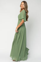 Styled flat-lay and hem view of olive Valetta maxi dress showcasing maxi length skirt and left-side slit for ease of movement.