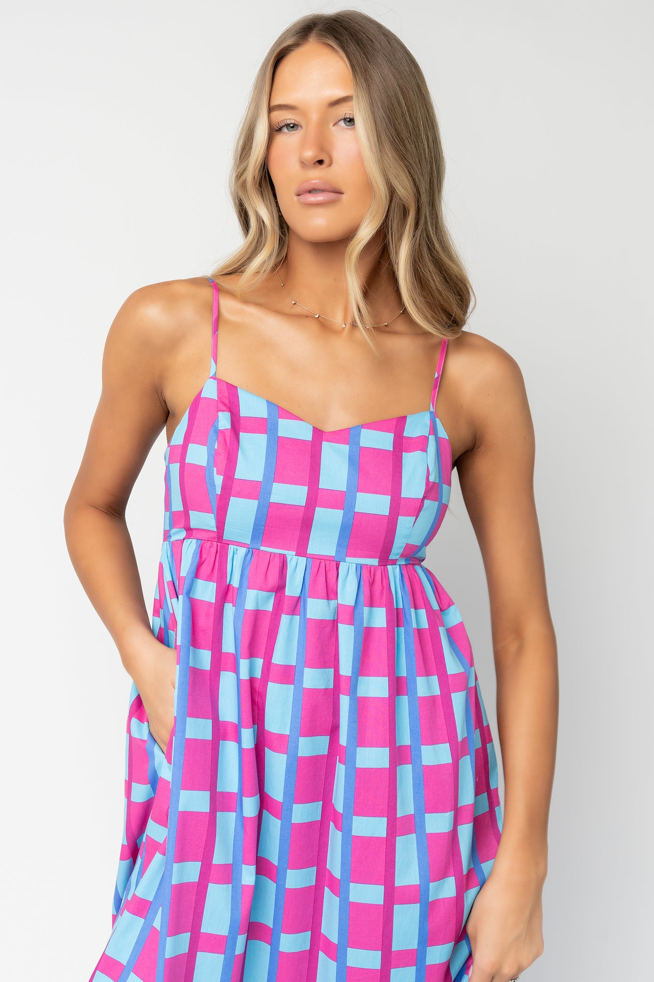 Close-up of pink-and-blue geometric check print and cotton texture; shows stitchwork and lining that reaches mid-thigh.