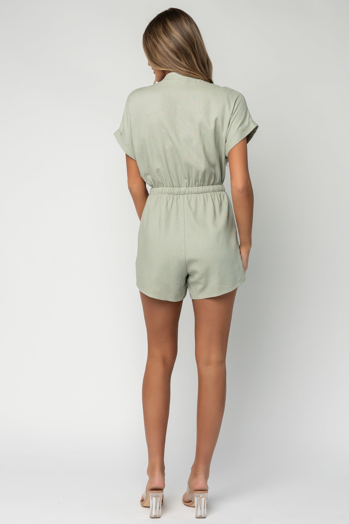 Back view of the Winnie romper in light sage displaying elastic drawstring waistband and fully lined shorts for added coverage.