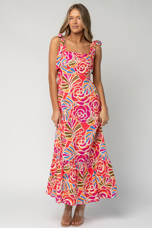 Front view of Sydney Maxi Dress in multi floral print on model showing straight neckline, adjustable shoulder ties, smocked back, and side pockets.