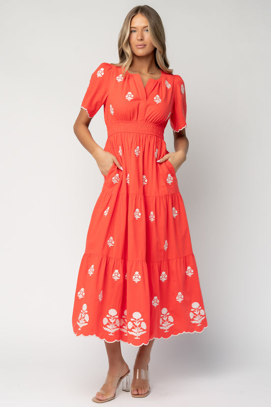 Front view of Delilah embroidered red maxi dress with off-white floral embroidery, split V-neck, scalloped short sleeves, and smocked waist.