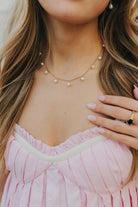 Close-up of The Rosie Pearl Necklace showing delicate 18K gold-plated chain and small white cultured pearl drops on a neutral background, highlighting finish and spacing.
