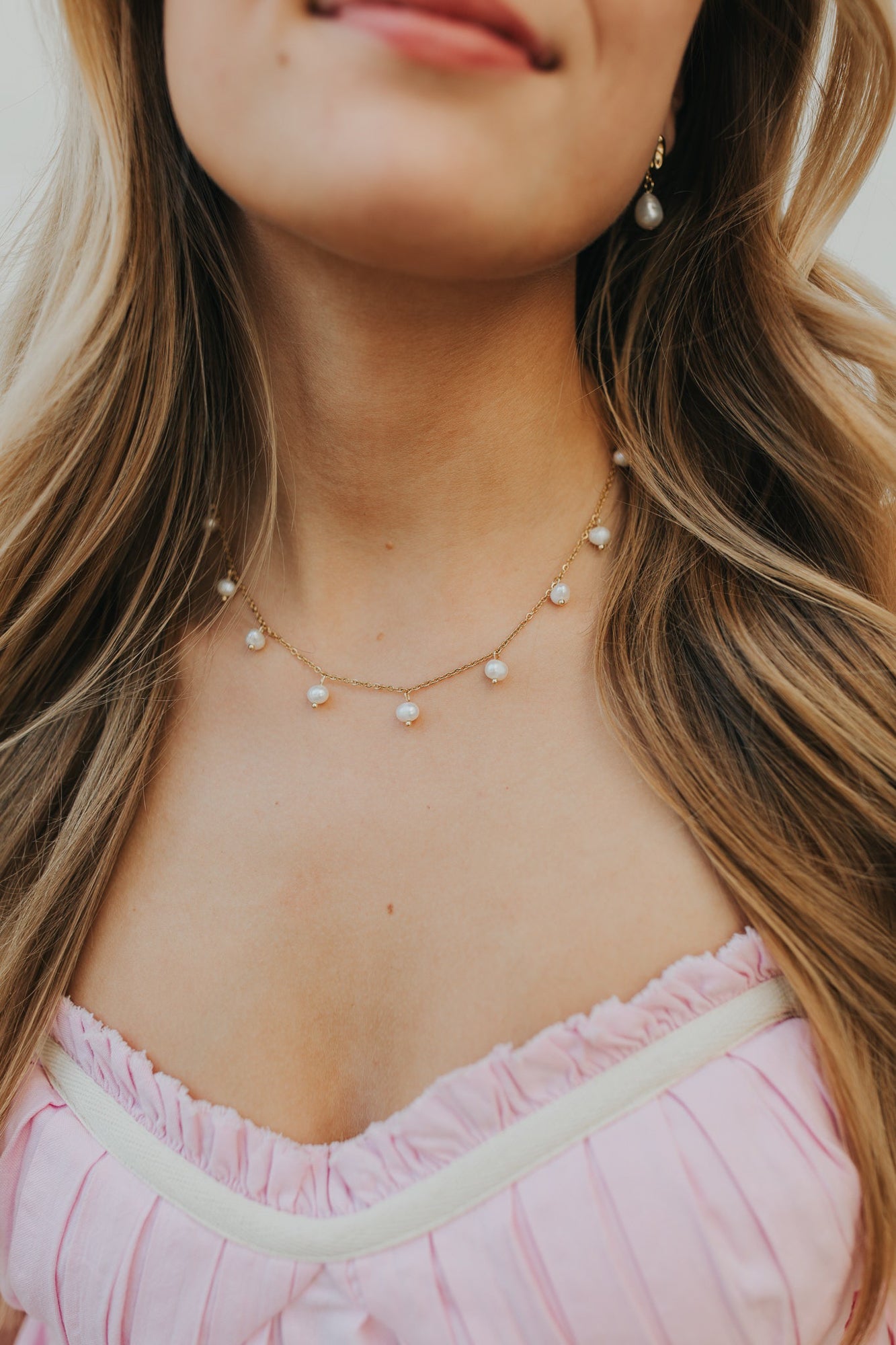 Product detail shot of petite cultured pearl drops and fine gold chain texture, emphasizing the plating finish and connection links for quality inspection.
