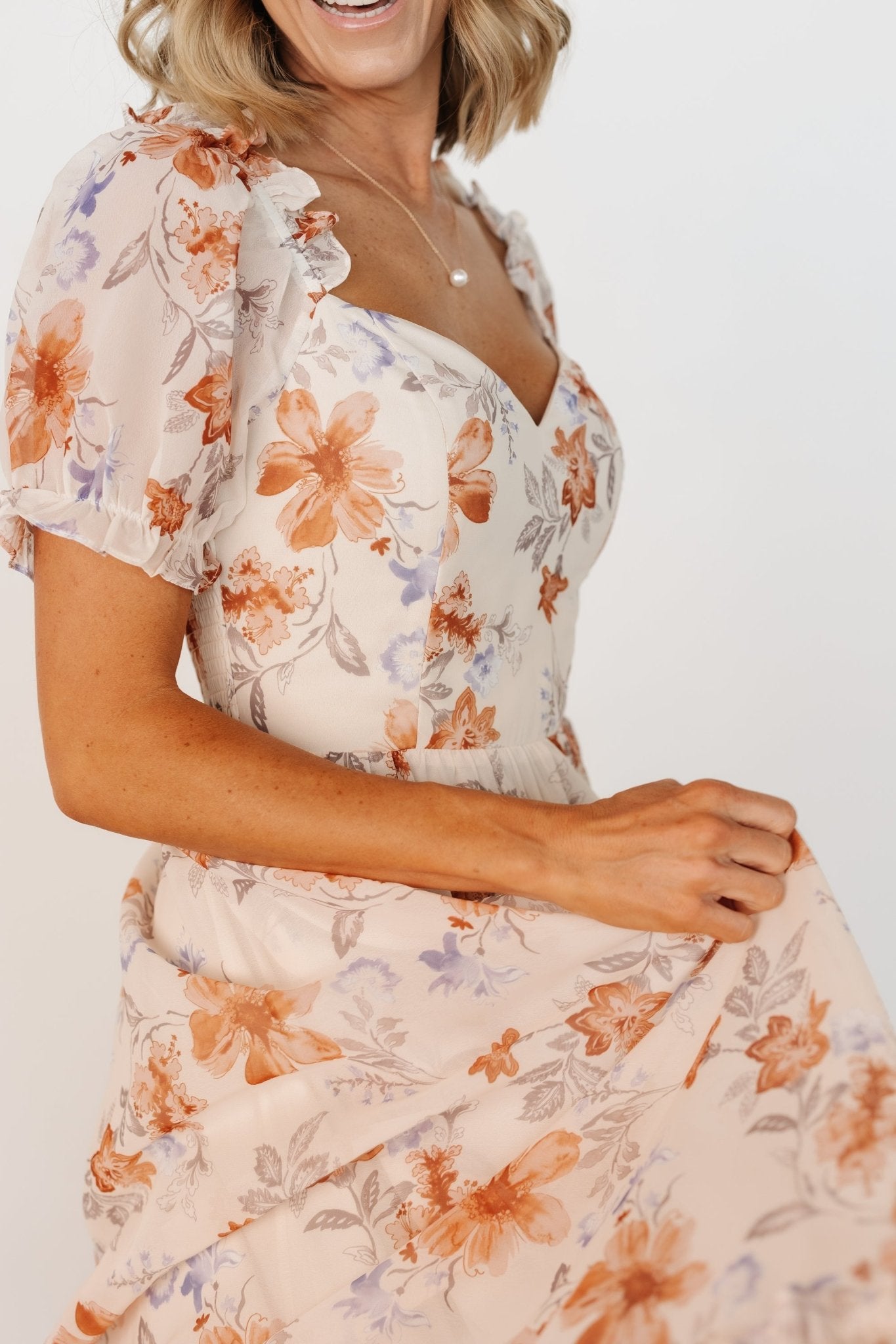 Fabric detail showing 100% polyester self and lining, lightweight drape, and printed floral motif on cream maxi dress.