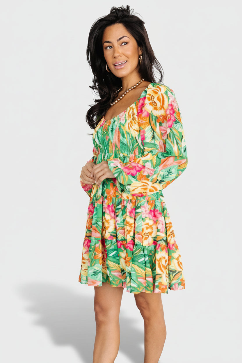 Back view of green multi-print chiffon short dress with elastic on shoulders and ruffle tiers on the skirt for added volume.