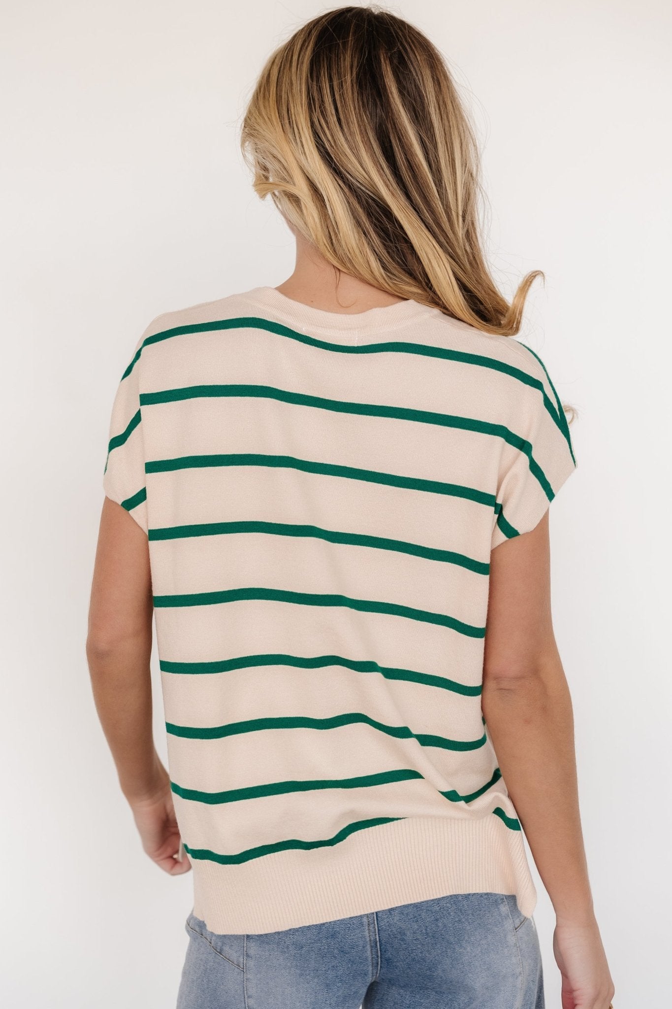 Lifestyle view of natural knit top with green stripes styled with denim, showing length, relaxed fit and short dolman sleeves for everyday wear.