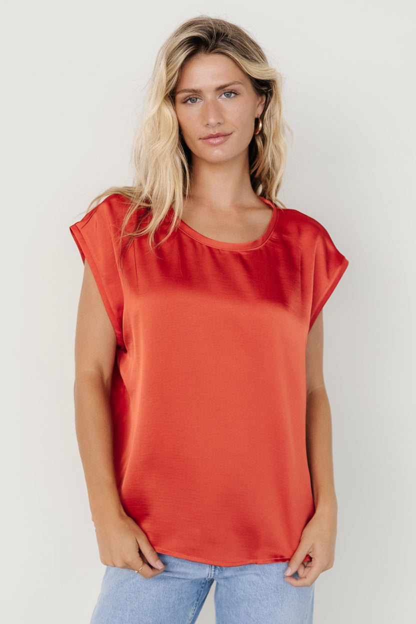 Front view of Adina satin-effect oversized rust top on a model; drapey silhouette, round neckline, low armholes, long sleeves visible.