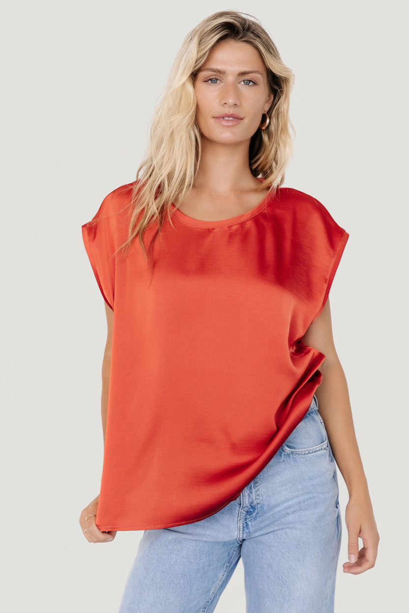 Back view of Adina oversized rust top on model; relaxed drape and low armholes visible, suitable for layering under jackets.