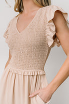 Side view of Afton smocked tiered midi dress in sand displaying functional side pocket and flutter sleeve silhouette.