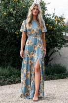 Model wearing Agnes satin maxi dress in vintage teal with gold florals, styled with belt tied at the waist for a tailored look.
