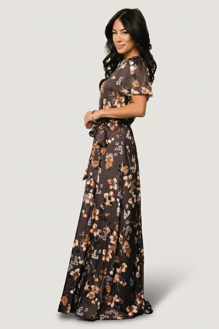 Styled flat-lay of brown floral satin maxi dress showing full silhouette, maxi length, and removable belt tie for styling options.
