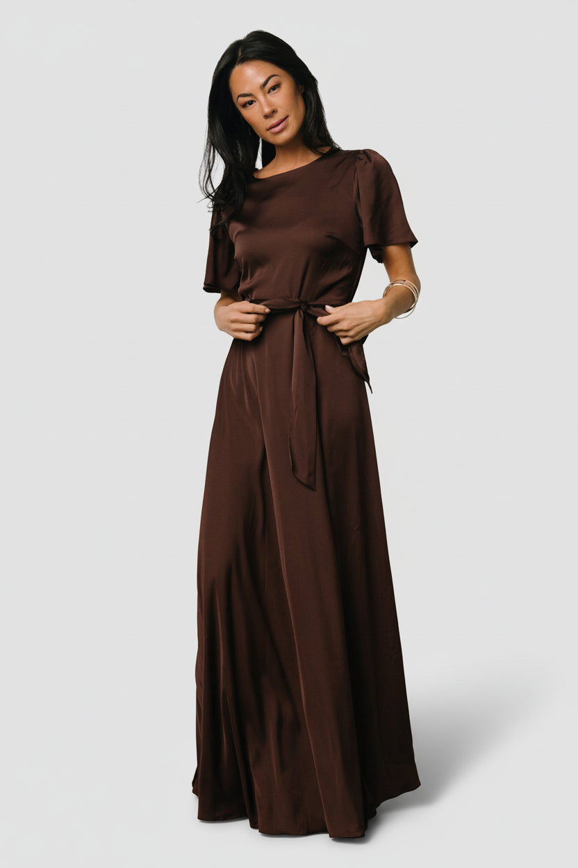 Front view of the Agnes satin maxi dress in espresso showing rounded neckline, flutter sleeves, removable waist tie, and flowing skirt with slit.