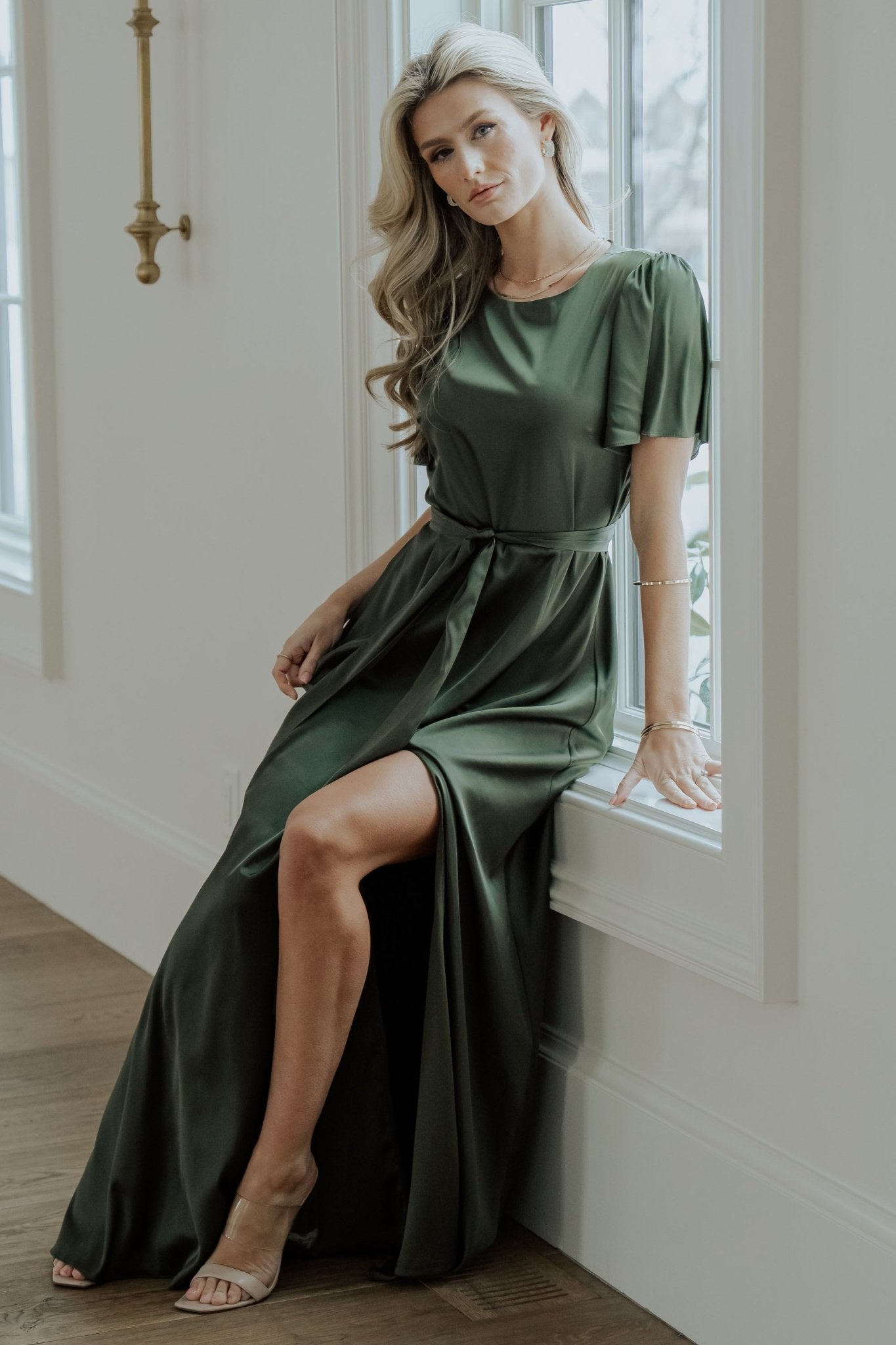 Close-up of the Agnes dress waist tie and side seam, emphasizing removable belt detail and soft satin drape in juniper green.