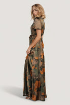 Model shot of olive floral satin maxi dress styled with heels to show length, drape, and how the sash defines the waist.