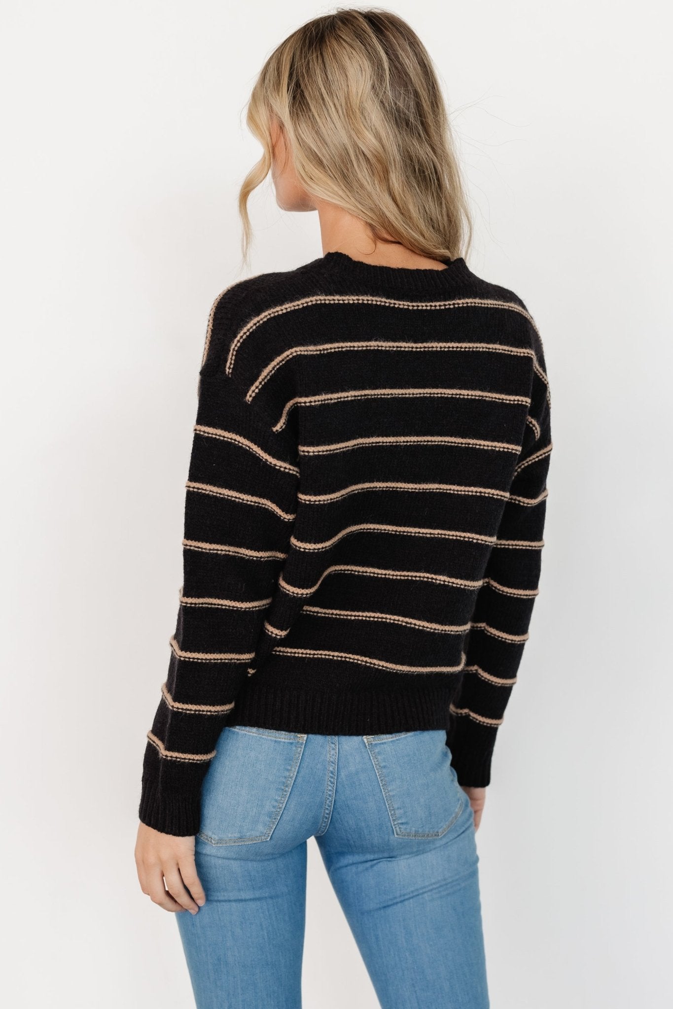 Back view of sweater on model illustrating relaxed shoulder line, overall drape, and stripe alignment through the body and sleeves.