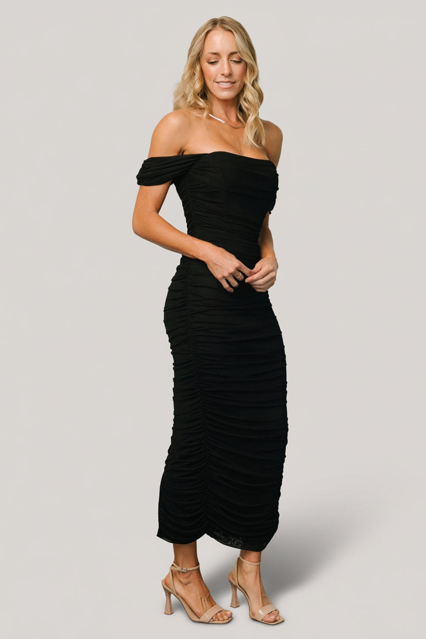 Front view of Alessandra black mesh midi dress on model showing off‑shoulder neckline, structured bust, ruched sides and fitted midi silhouette for evening wear.