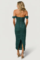 Model poses in peacock mesh midi dress with off-shoulder styling; visible zipper at the back, contoured bust, and smooth lining beneath the sheer sleeves for contrast and structure.