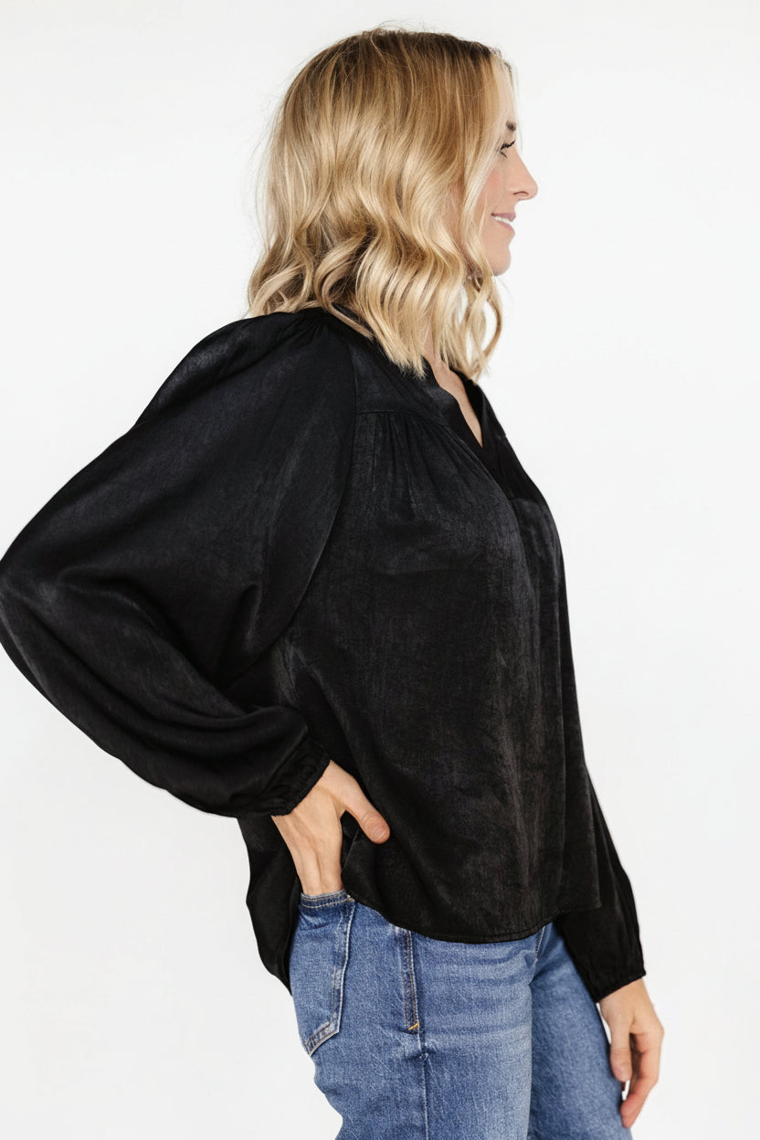 Back view of the Alina blouse in black showing the seamed back yoke with subtle gathering and the relaxed, roomy fit across the torso.