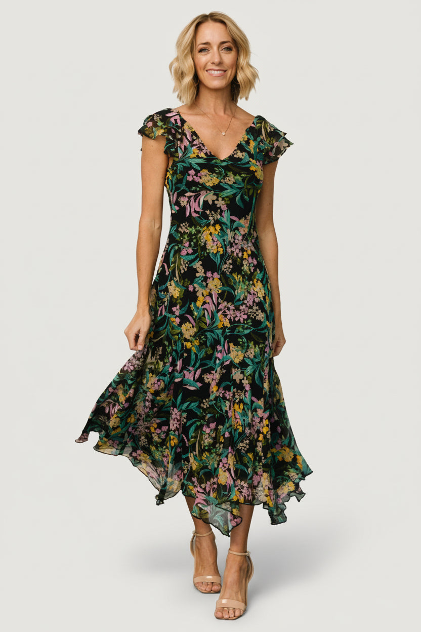 Front view of model wearing a black floral chiffon maxi dress with V-neck, short flutter sleeves, and flowing skirt, fully lined.