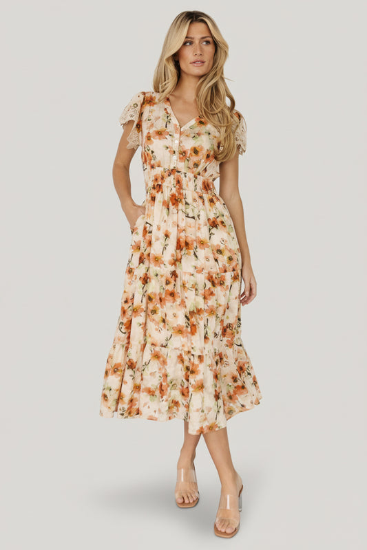 Front full-length view of the Aliyah Midi Dress in cream coral floral, showing V-neck, functional buttons, lace-trim sleeves, and smocked waist.