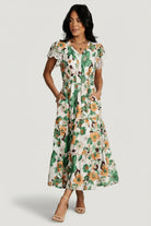 Front model view of Aliyah smocked midi dress in cream with orange and green floral print, V-neck, lace-trim short sleeves, smocked waist and pockets.